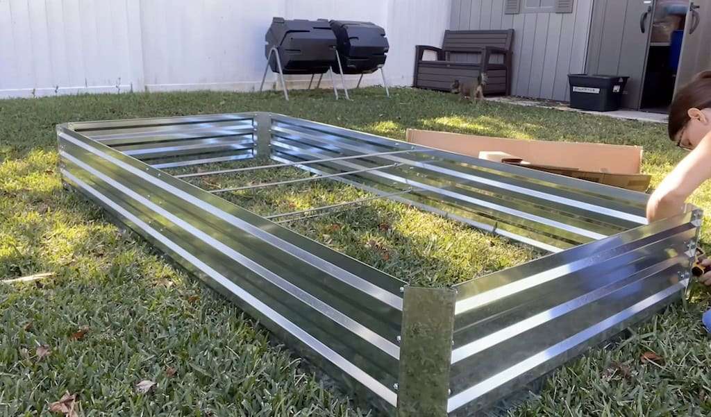 Woman assembling a metal raised garden bed