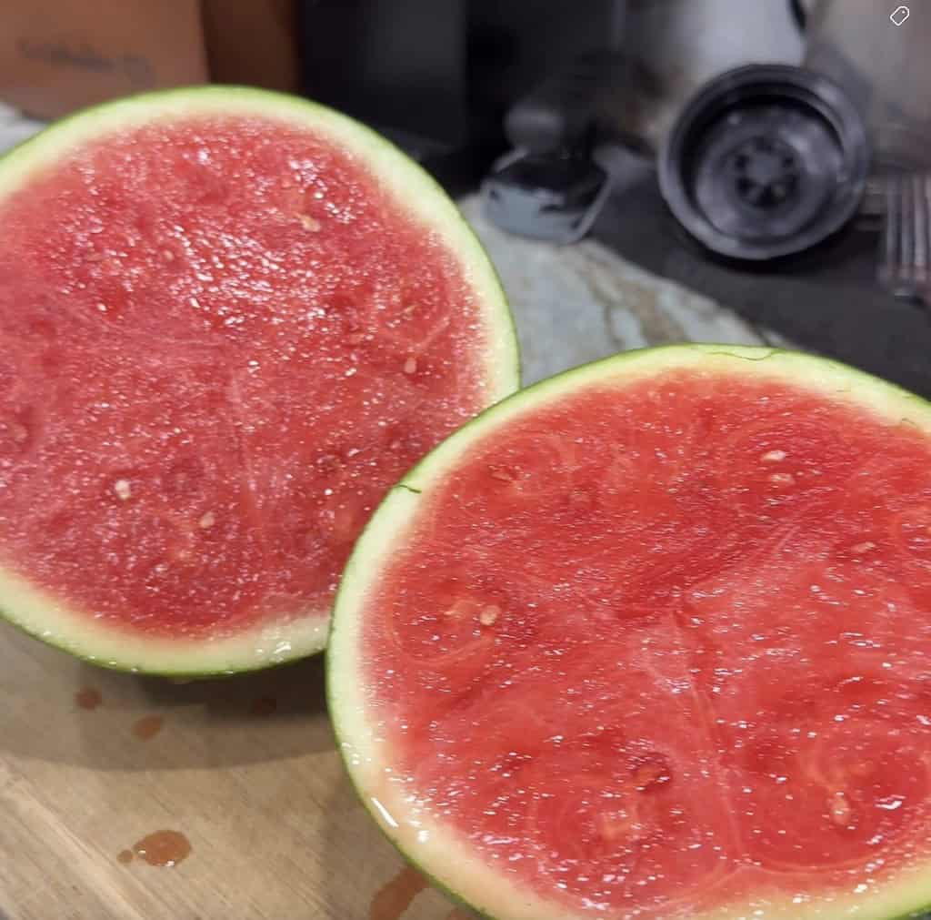 Seedless watermelon cut in half on a kitchen counter showing the inside.